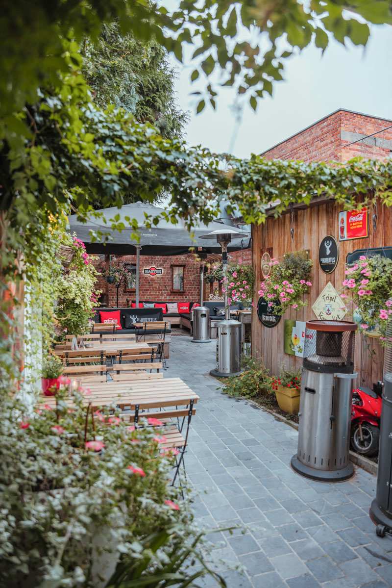 Sfeerbeeld van het terras van bar de q met verschillende houten tafels en stoelen.