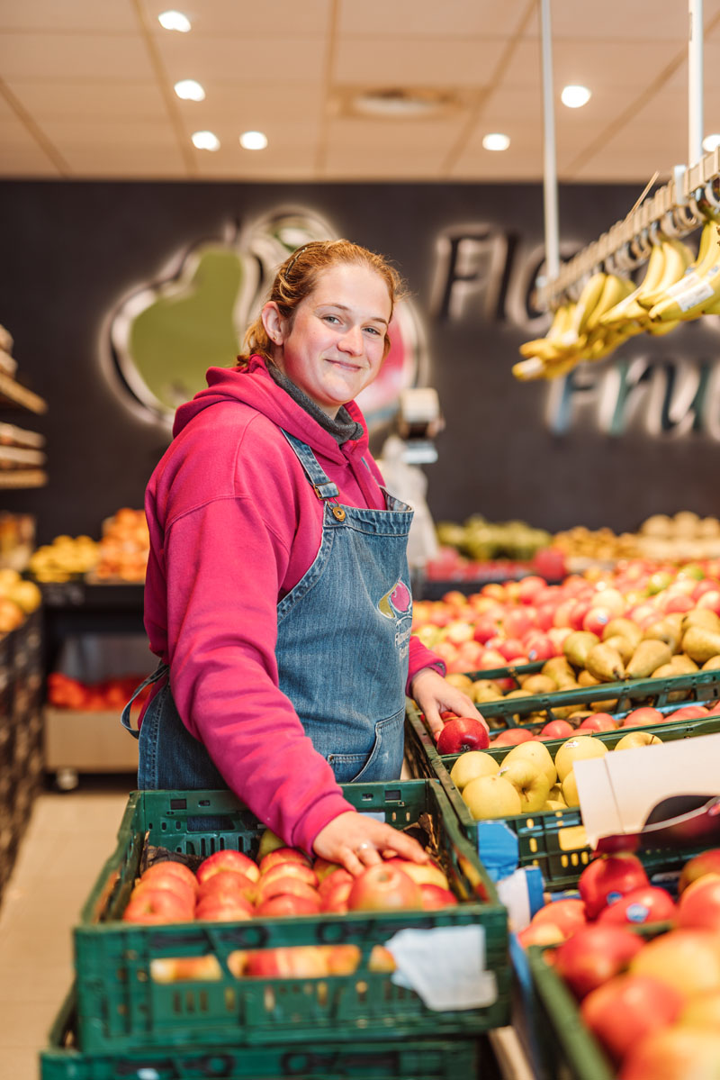 Eén van de medewerkers vult het fruit aan