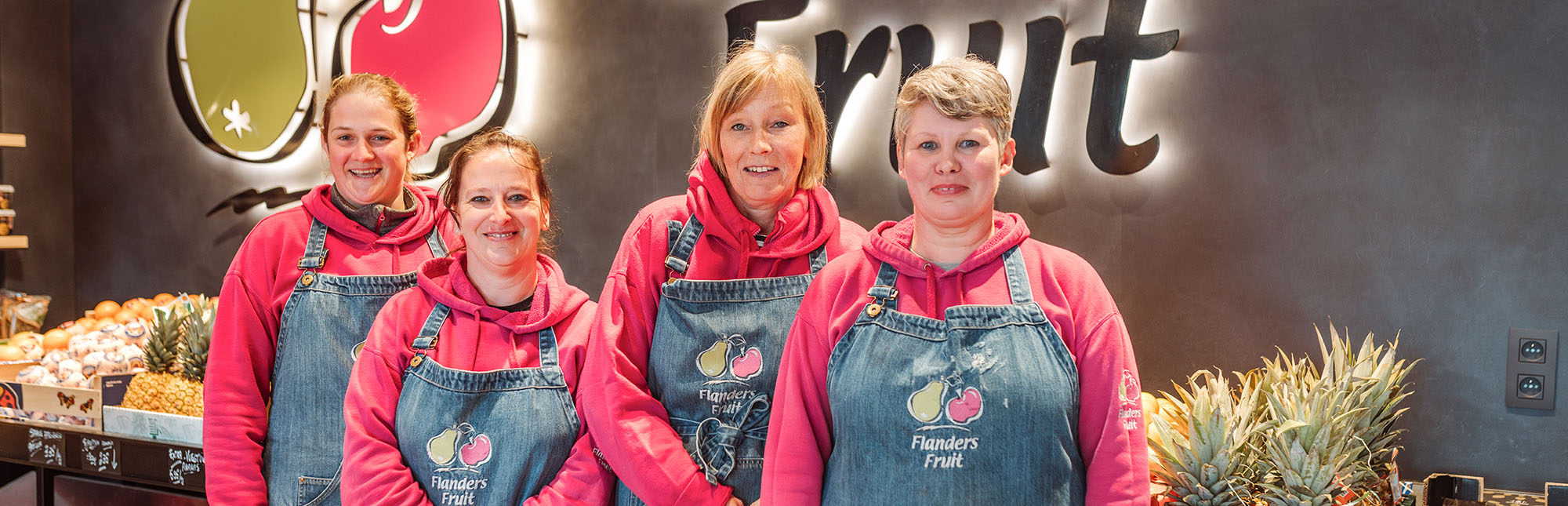 Portret van het Flanders Fruit team met fuchsia fleece truien en jeansschorten aan