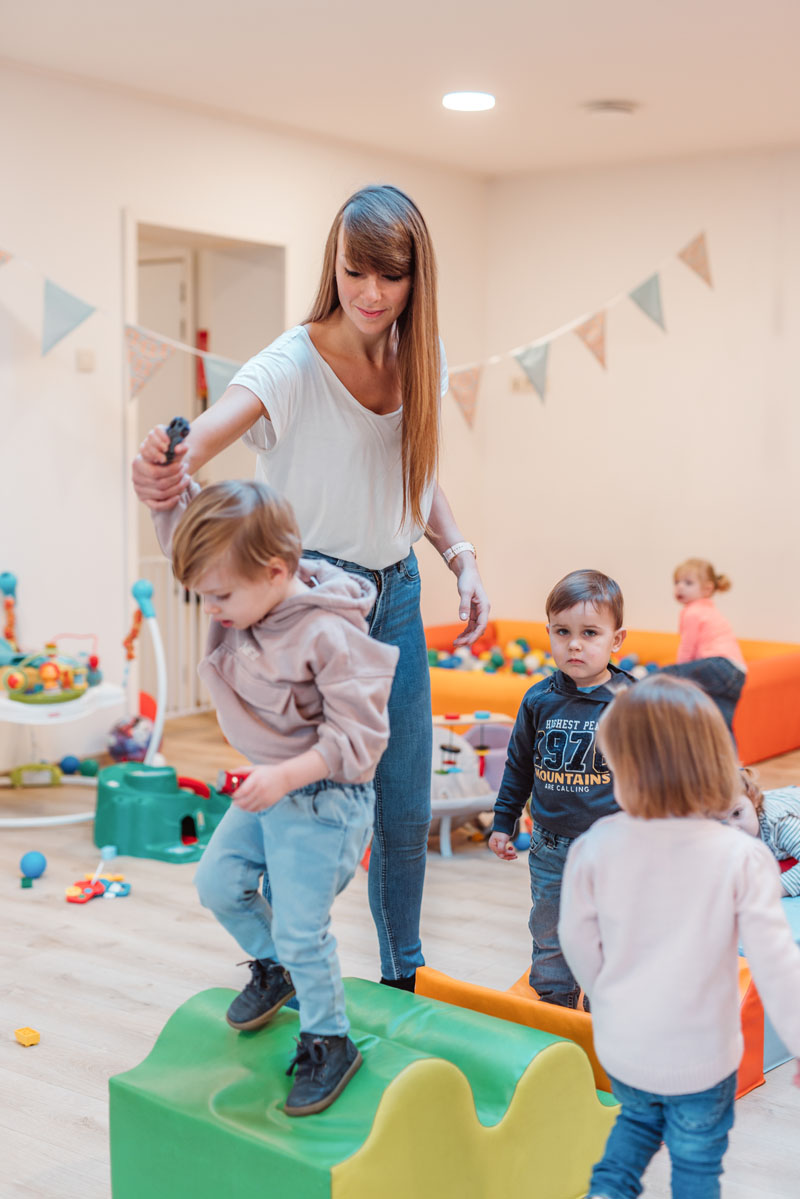 Kinderverzorgster helpt kinderen over een parcous