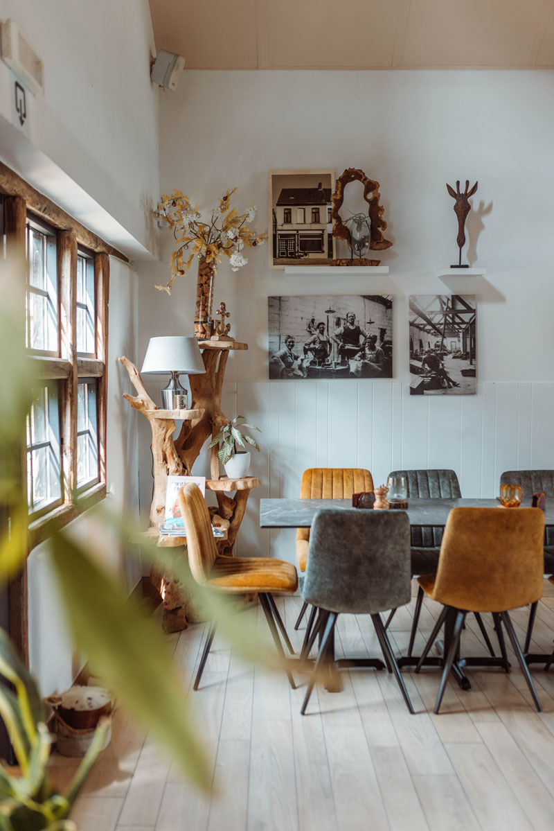 Detail van het interieur met enkele stoelen een tafel en wanddecoratie.