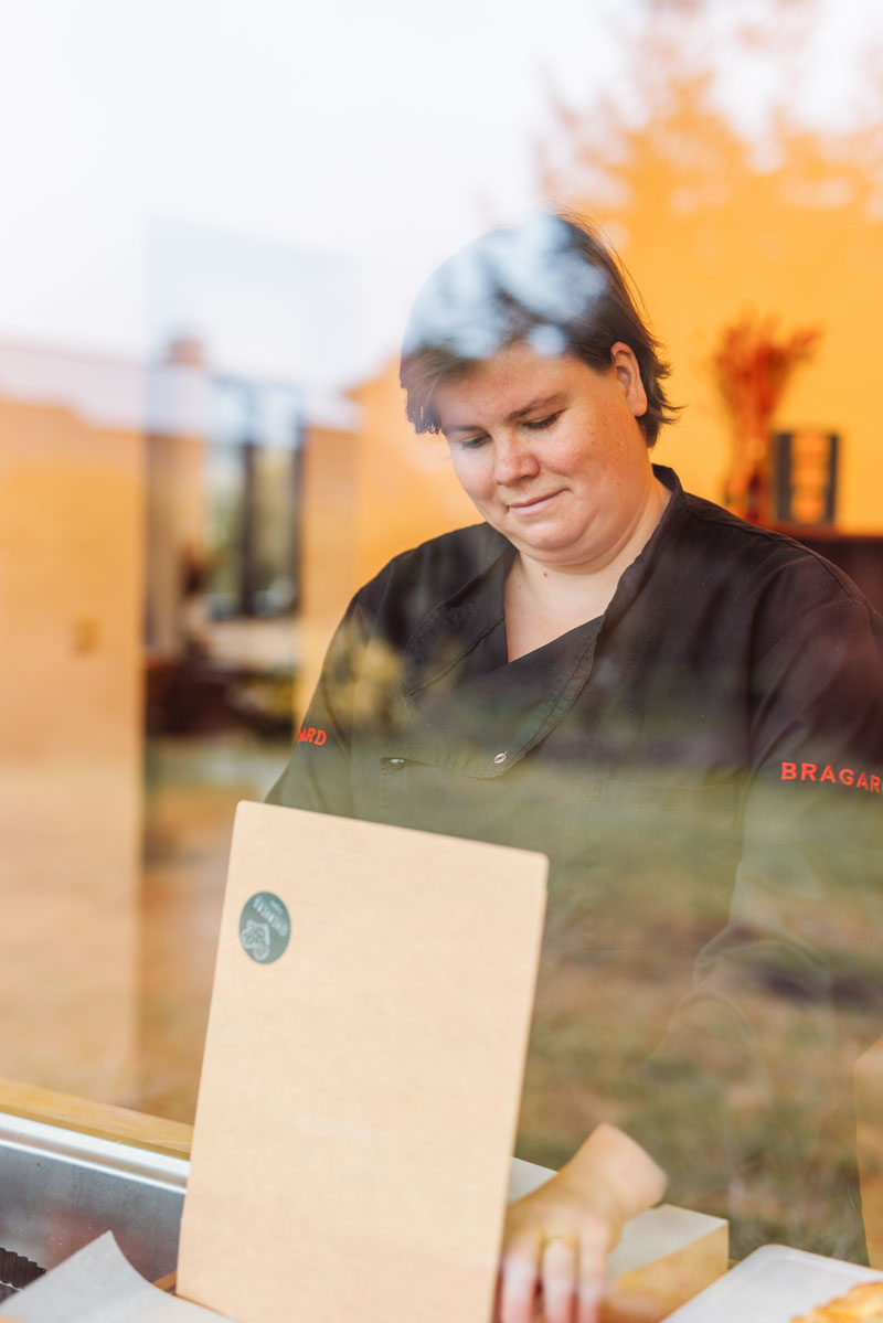 Glimlachende Sigrid die aan het werk is door het raam gefotografeerd.