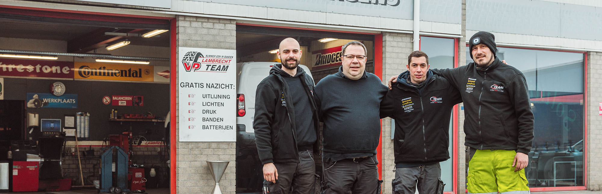 Portret van het 4 koppige Qteam Eeklo dat voor de bandencentrale staat.