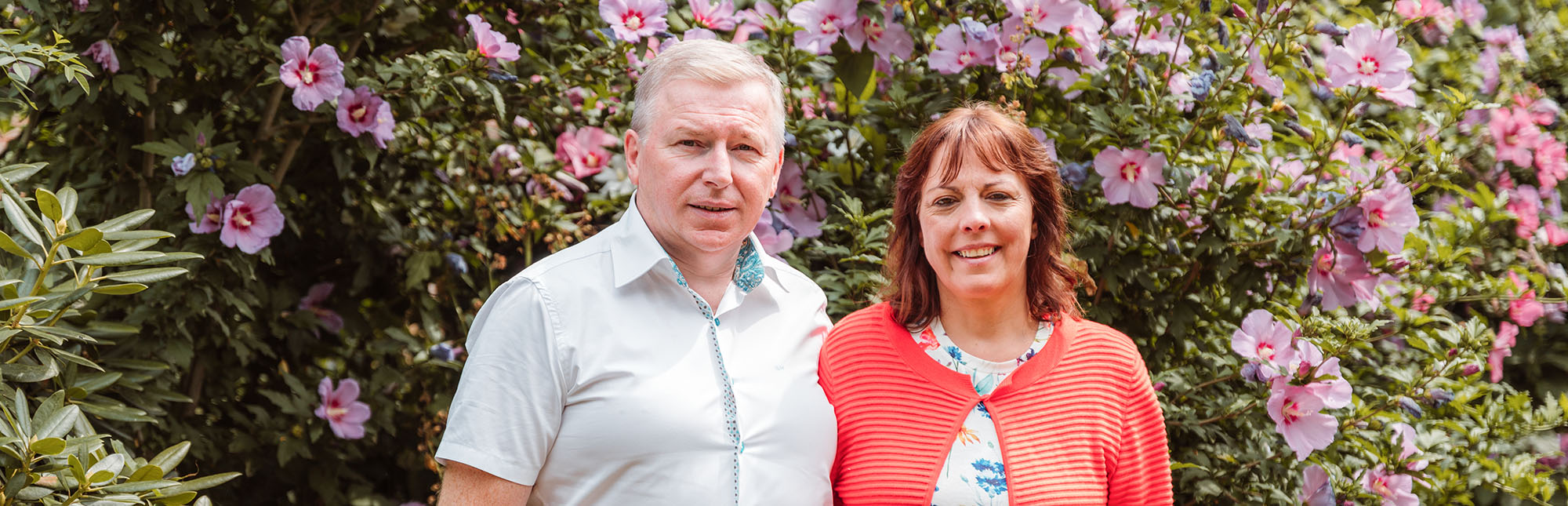 Portret van Wim en Ines met bloemenstruik achter hen.