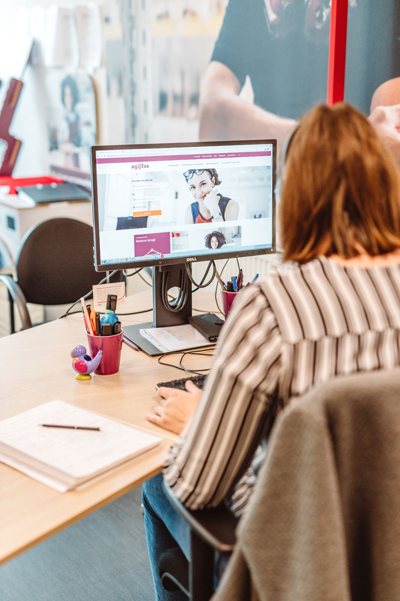 Close up: meekijkend over de schouder van een medewerker die op haar computer werkt.