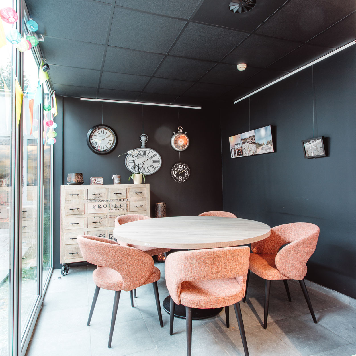 Gezellige zithoek met een ronde houten tafel en 5 roze kuipstoelen.