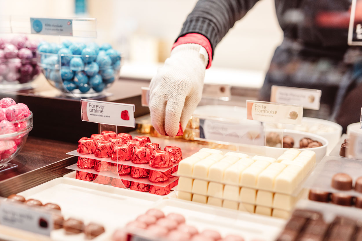 Hand met witte handschoen die pralines neemt.