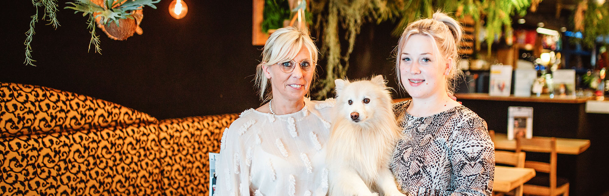 Portret van zaakvoerders Anneke en Virgina met hun hondje in hun zaak.