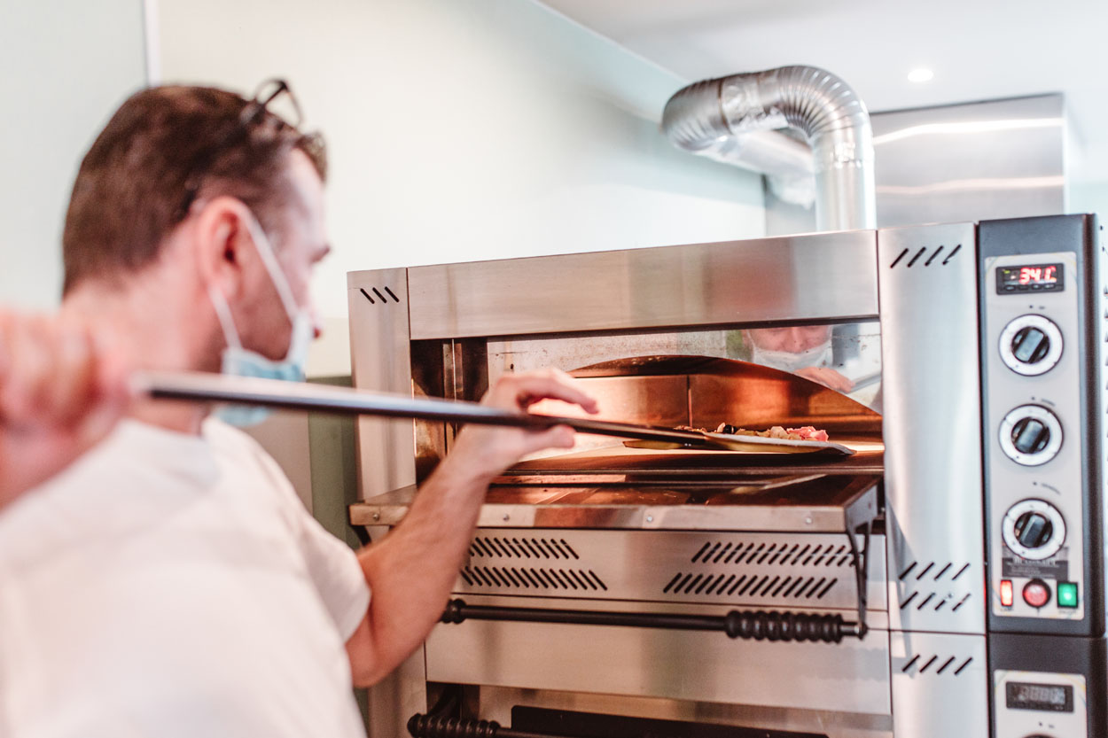 Pizza wordt in de oven geschoven.