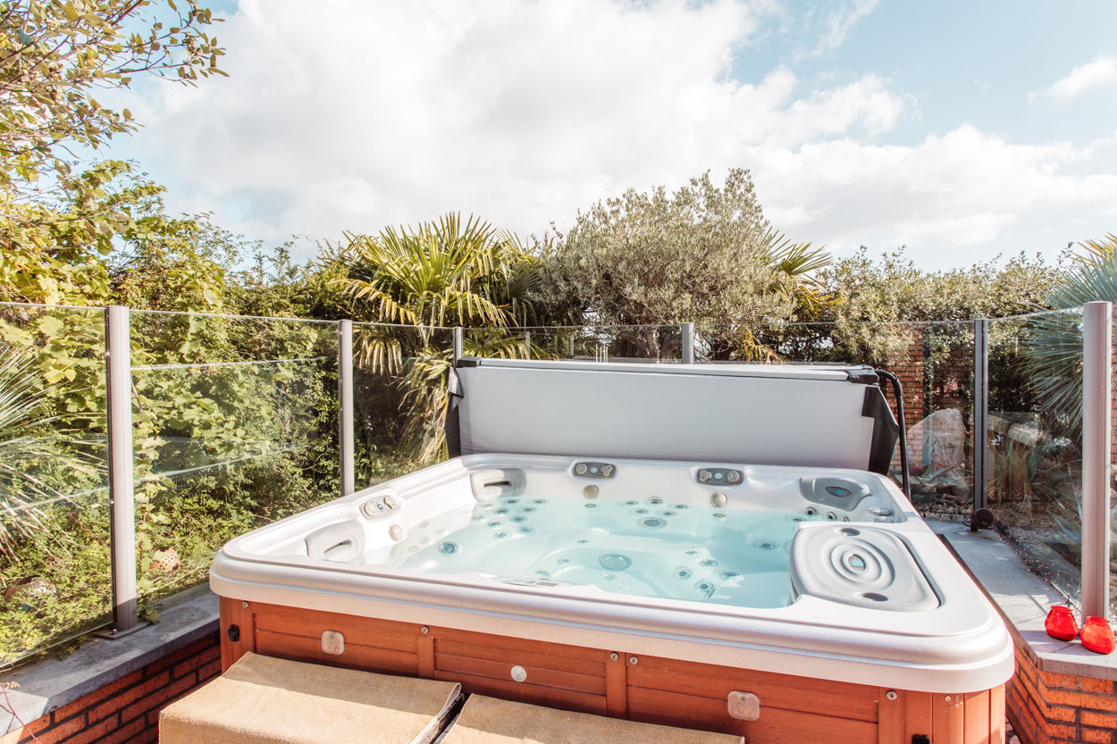 Luxe grote jacuzzi met tropische planten erachter.