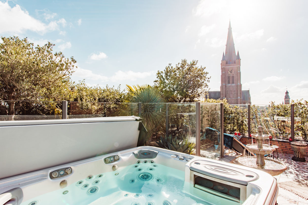 Grote luxe jacuzzi met op de achtergrond de kerktoren van Eeklo.