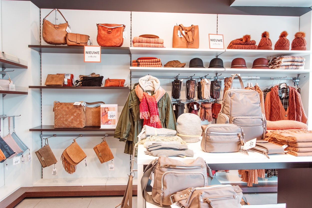 handtassen, sjaals en jassen op rekken in de winkel