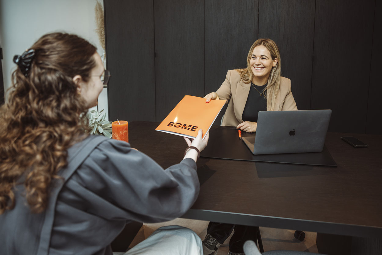 Stefanie overhandigt een oranje farde aan een klant.