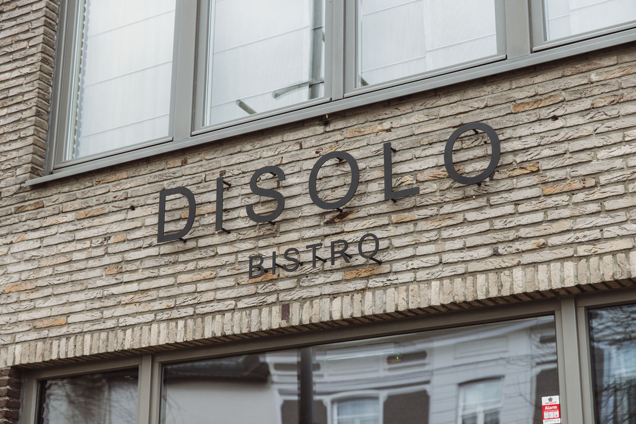 Het logo Van Bistro Disolo is strakke zwarte letters boven de deur.